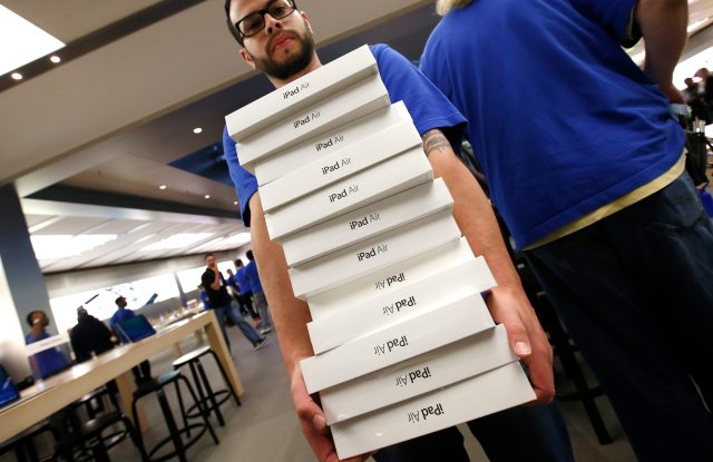An employee carries a stack of new Apple iPad Air tablets inside the Apple Store on New York's fifth avenue after the new iPad went on sale