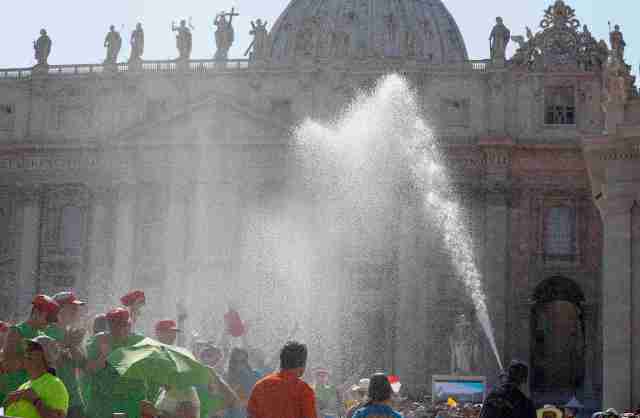 A firefighter sprays water to refresh faithfuls before a meeting with Pope Francis in St Peter's Square at the Vatican