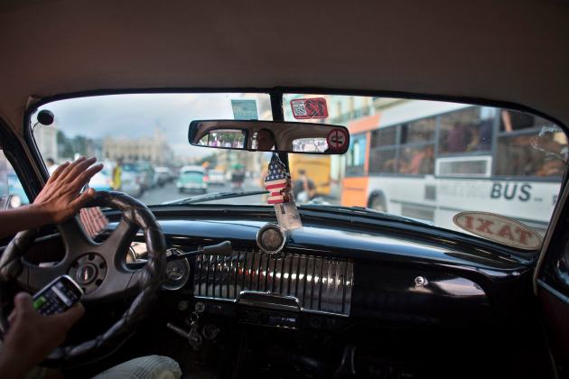 Taxi driver drives a vintage car in downtown Havana