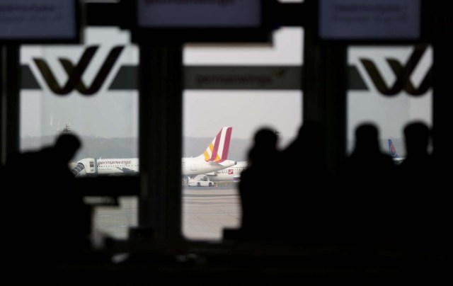 Passengers are silhouetted against a window at the Germanwings check-in desk at Dusseldorf airport