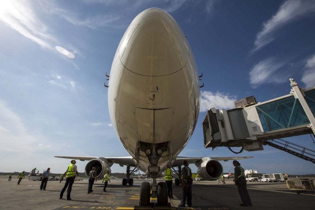 Workers stand next to an aircraft at a runway on the Simon Bolivar airport in Caracas July 17, 2015. Venezuelan airline Avior is purchasing 12 used planes to offer new international routes from the South American nation, where foreign carriers have slashed flights due to currency controls. Avior President Jorge Anez said in an interview on Thursday that the company was purchasing six planes from Europe's Airbus Group and six from Chicago-based Boeing CO for a total of about $150 million. REUTERS/Marco Bello