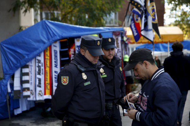 Spanish National Police officers check a man's identification as they stand guard outside the Santiago Bernabeu stadium before the 'Clasico' soccer match between Real Madrid and Barcelona in Madrid, Spain, November 21, 2015. REUTERS/Susana Vera