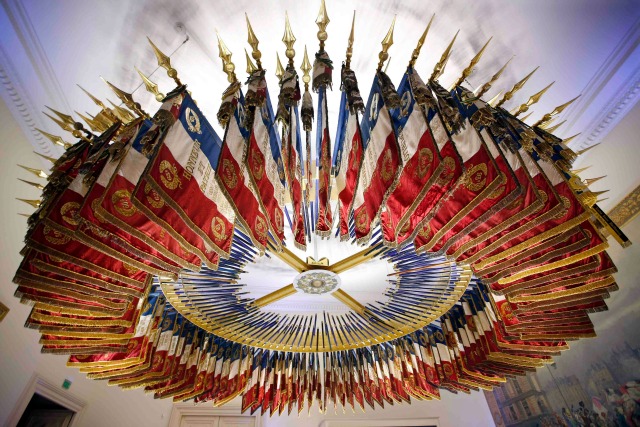 La tricolor, banderas y pancartas de 182 regimientos militares franceses disueltas azules, blancos y rojos están dispuestos en un círculo, ya que cuelgan del techo en la habitación Emblemas (salle des Emblemes) en el castillo de Vincennes, cerca de París, Francia, 2 de diciembre de 2015. REUTERS / Charles Platiau