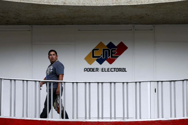 A man walks past a logo of the National Electoral Council (CNE) at its headquarters in Caracas December 2, 2015. Venezuela will hold parliamentary elections on December 6. REUTERS/Carlos Garcia Rawlins