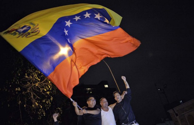 Venezuelan opposition supporters celebrate the results of the legislative election in Caracas, on the early morning December 7, 2015. Venezuela's opposition won --at least--a majority of 99 out of 167 seats in the state legislature, electoral authorities said Monday, the first such shift in power in congress in 16 years. / AFP / LUIS ROBAYO