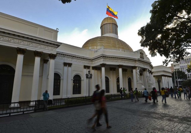 People walk past the National Assembly building in Caracas, on December 7, 2015. Venezuela's jubilant opposition vowed Monday to drag the oil-rich country out of its economic crisis and free political prisoners after winning control of congress from socialist President Nicolas Maduro. AFP  PHOTO/Luis Robayo / AFP / LUIS ROBAYO