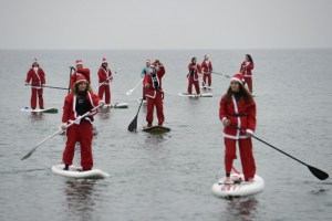 Vestidos de Santa Claus practicaron paddle surf en la playa de la Barceloneta (Fotos)