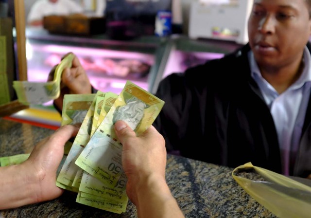 A cashier counts bolivar notes at a butchery in a public market in Caracas, Venezuela January 22, 2016. Venezuela's opposition refused on Friday to approve President Nicolas Maduro's "economic emergency" decree in Congress, saying it offered no solutions for the OPEC nation's increasingly disastrous recession. Underlining the grave situation in Venezuela, where a plunge in oil prices has compounded dysfunctional policies, the International Monetary Fund on Friday forecast an 8 percent drop in gross domestic product and 720 percent inflation this year. REUTERS/Marco Bello