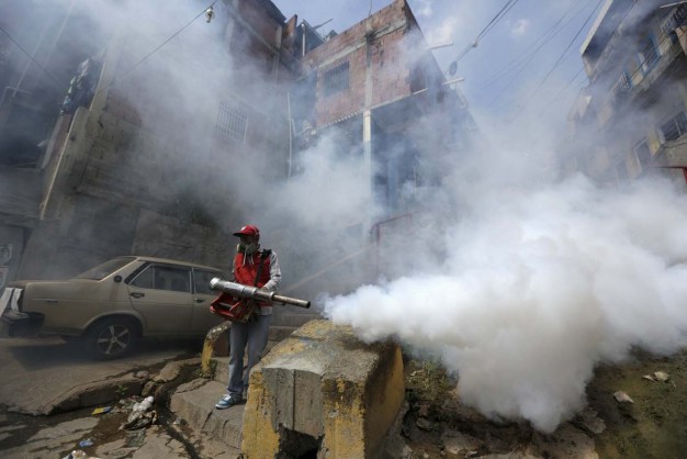 A Venezuelan health worker fumigates the Valle slum to help control the spread of the mosquito-borne Zika virus in Caracas, January 28, 2016. REUTERS/Marco Bello