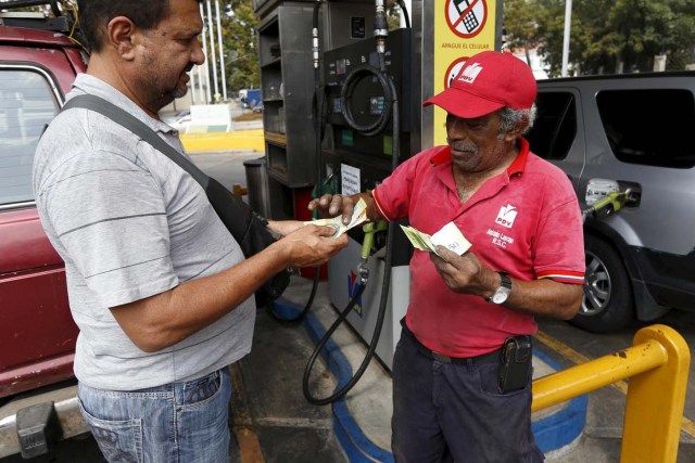 A man pays after filling up his car with fuel at a gas station which belongs to PDVSA in Caracas, Venezuela February 19, 2016. REUTERS/Marco Bello