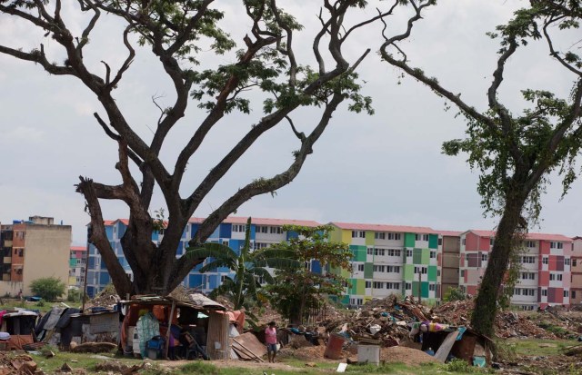 Una mujer busca agua en un rancho frente a la comunidad utópica Ciudad Socialista de Hugo Chávez el 16 de septiembre del 2015 en Valencia, Venezuela. La Guardia Nacional destruyó el rancho, construido en tierras del gobierno reservadas para una segunda fase de la comunidad utópica, pero los ranchos reaparecen al poco tiempo. Muchos de sus habitantes sueñan con ser admitidos alguna vez en la ciudad utópica donde casi todos los servicios son subsidiados.  (AP Photo/Fernando Llano)