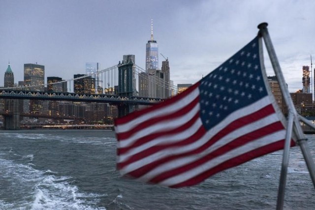 El puente Manhattan se ve en el fondo mientras un barco con una bandera de Estados Unidos cruza el Río Este, en Nueva York. 21 de septiembre de 2015. El crecimiento económico de Estados Unidos se frenó bruscamente en el cuarto trimestre debido a que las empresas incrementaron los esfuerzos para reducir un exceso de inventarios, mientras que la fortaleza del dólar y la debilidad de la demanda global pesaron sobre las exportaciones. REUTERS/Darren Ornitz