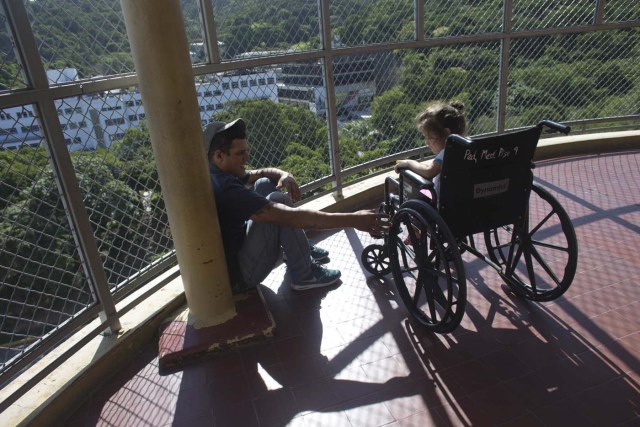 En esta imagen del 17 de agosto de 2016, Maykol Pacheco se sienta con su hija de tres años Ashley, que se recupera de una infección estafilocócica, en un balcón del Hospital Universitario de Caracas, en Venezuela. (AP Foto/Ariana Cubillos)