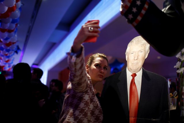 A woman photographs herself with a cardboard figure of U.S. Republican presidential candidate Donald Trump in Berlin, Germany, November 8, 2016. REUTERS/Axel Schmidt