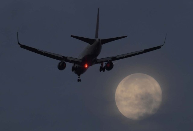 A passenger aircraft makes it's landing approach to Heathrow airport in front of a "super moon" at dawn in west London, Britain, October 17, 2016. REUTERS/Toby Melville