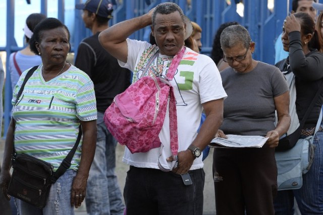 People queue outside Venezuela's Central Bank (BCV) in Caracas in an attempt to change 100 Bolivar notes, on December 16, 2016. Venezuelans lined up to deposit 100-unit banknotes before they turned worthless, but replacement bills had yet to arrive, increasing the cash chaos in the country with the world's highest inflation. Venezuelans are stuck in currency limbo after President Nicolas Maduro ordered the 100-bolivar note -- the largest denomination, currently worth about three US cents -- removed from circulation in 72 hours. / AFP PHOTO / FEDERICO PARRA