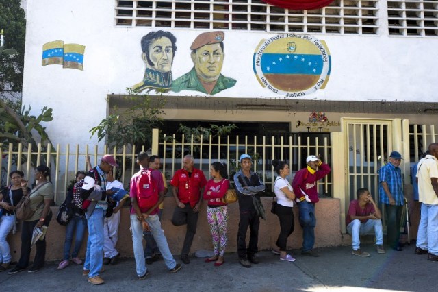 People queue outside Venezuela's Central Bank (BCV) in Caracas in an attempt to change 100 Bolivar notes, on December 16, 2016. Venezuelans lined up to deposit 100-unit banknotes before they turned worthless, but replacement bills had yet to arrive, increasing the cash chaos in the country with the world's highest inflation. Venezuelans are stuck in currency limbo after President Nicolas Maduro ordered the 100-bolivar note -- the largest denomination, currently worth about three US cents -- removed from circulation in 72 hours. / AFP PHOTO / FEDERICO PARRA