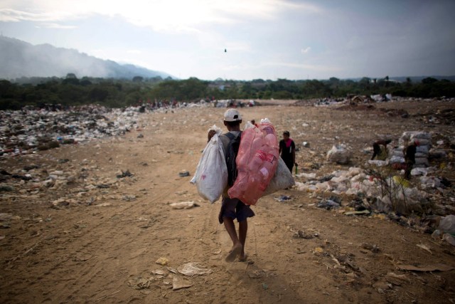 En esta imagen, tomada el 1 de noviembre de 2016, un hombre carga con bolsas de material reciclable que recogió en un vertedero en Puerto Cabello, Venezuela, la ciudad portuaria a donde llega la mayoría de la comida importada del país. Cuando la comida se echa a perder, los militares tratan de deshacerse de ella discretamente.Residentes dijeron que pudieron recuperar granos y comida para animales arrojada por los militares. (AP Foto/Ariana Cubillos)