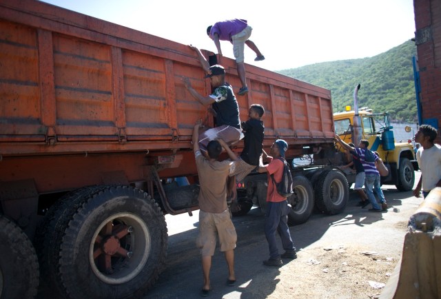 En esta imagen del 14 de noviembre de 2016, jóvenes trepando a un camión vacío de comida para buscar granos sobrantes, durante una parada del vehículo ante el puerto de Puerto Cabello, Venezuela, la ciudad portuaria por la que pasan la mayoría de importaciones de alimentos del país. El general retirado Antonio Rivero, que rompió con el gobierno en 2014, dijo que el presidente, Nicolás Maduro, puso al ejército a cargo de la comida para evitar que soldados hambrientos participaran en un alzamiento contra el cada vez más impopular gobierno. (AP Foto/Ariana Cubillos)