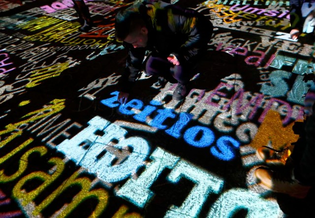 A man uses a chalk to draw the sign displayed during the laser installation "Time Drifts Cologne" before New Year celebrations for 2017 in Cologne, Germany, December 31, 2016. REUTERS/Wolfgang Rattay