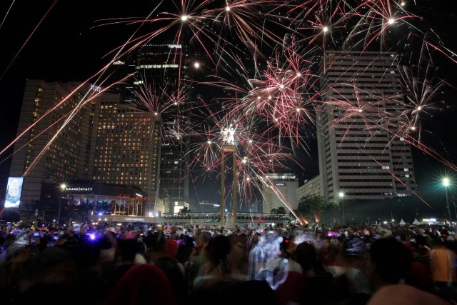 People watch fireworks explode around the Selamat Datang Monument during New Year's Eve celebrations in Jakarta, Indonesia December 31, 2016. REUTERS/Beawiharta