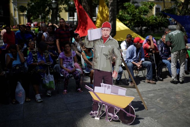 A cardboard cut-out of Venezuela's late President Hugo Chavez is seen as people wait to apply for a card that will register them for government social programmes, in Caracas, Venezuela January 20, 2017. REUTERS/Marco Bello