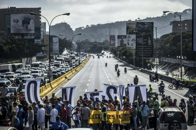 Opponents of Venezuelan President Nicolas Maduro show banners during a protest at the main highway of Caracas on January 24, 2017. Venezuelan opponents protested to demand early elections, with the aim of ousting President Nicolas Maduro, who they blame for the profound political and economic crisis that has the country in its grip. / AFP PHOTO / JUAN BARRETO