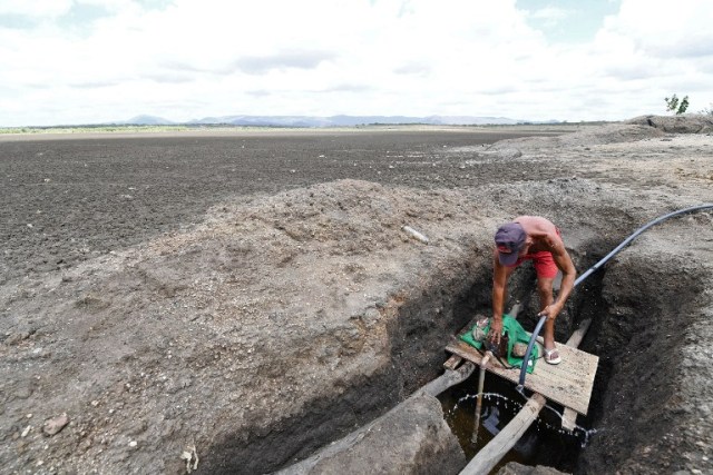 A man operates a water pump at the dry Cedro reservoir in Quixada, Ceara State, on February 8, 2017. The situation of Brazil's oldest reservoir sumps up the devastiting effects -human and environmental- of the worst drought of the century in the northeast of the country. / AFP PHOTO / EVARISTO SA / TO GO WITH AFP STORY BY CAROLA SOLE