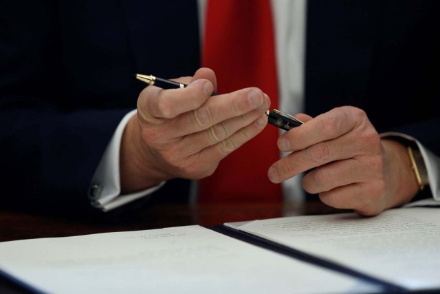 U.S. President Donald Trump prepares to sign an executive order on regulatory reform at his desk in the Oval Office at the White House, U.S. February 24, 2017. REUTERS/Jonathan Ernst