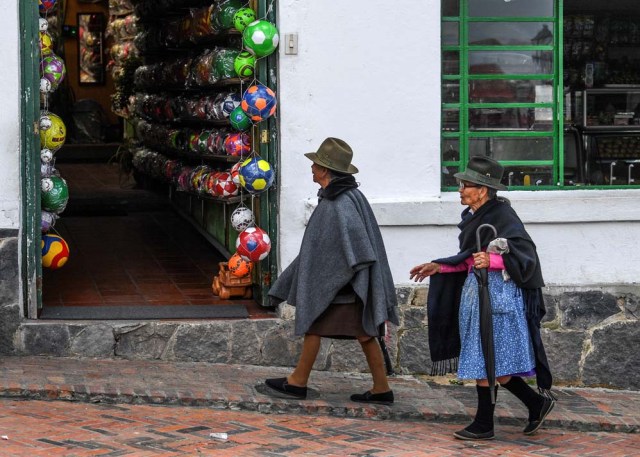 Elderly women pass by a ball factory in Mongui, in the Colombian department of Boyaca, on February 13, 2017. Mongui, in the central mountains of Colombia, has about 20 football factories that make balls mainly for football and micro-football. About a quarter of the town's 4,900 inhabitants work in these factories. / AFP PHOTO / Luis ACOSTA