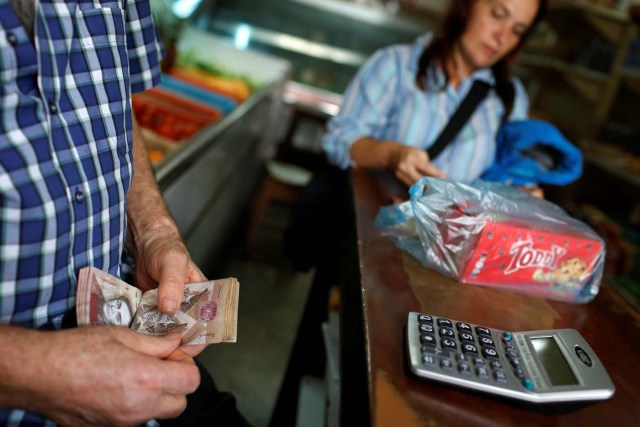 Jose Gomes (L) counts Venezuelan bolivar notes at his supermarket checkout line in Caracas, Venezuela March 9, 2017. REUTERS/Carlos Garcia Rawlins