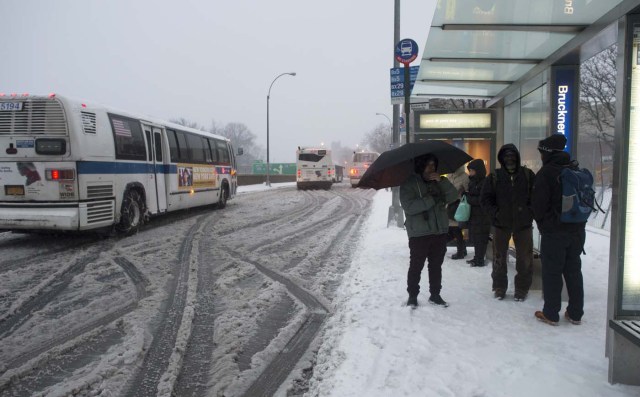 Passengers wait to board buses in the Bronx Borough March 14, 2017 in New York.  Winter Storm Stella dumped snow and sleet Tuesday across the northeastern United States where thousands of flights were canceled and schools closed, but appeared less severe than initially forecast. After daybreak the National Weather Service (NWS) revised down its predicted snow accumulation for the city of New York, saying that the storm had moved across the coast.  / AFP PHOTO / DON EMMERT