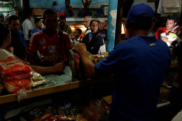 A man carrying a baby queues to try and buy food in a market in Caracas, Venezuela March 17, 2017. REUTERS/Carlos Garcia Rawlins SEARCH "GARCIA QUEUEING" FOR THIS STORY. SEARCH "WIDER IMAGE" FOR ALL STORIES.
