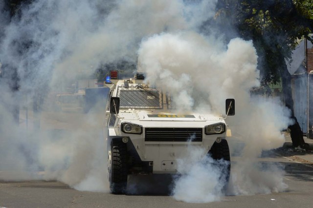 Riot police in an armoured vehicle try to disperse demonstrators during a protest against Venezuelan President Nicolas Maduro, in Caracas on April 20, 2017. Venezuelan riot police fired tear gas Thursday at groups of protesters seeking to oust President Nicolas Maduro, who have vowed new mass marches after a day of deadly unrest. Police in western Caracas broke up scores of opposition protesters trying to join a larger march, though there was no immediate repeat of Wednesday's violent clashes, which left three people dead. / AFP PHOTO / Federico PARRA