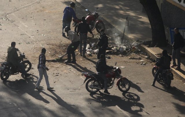 Los agentes de las fuerzas de seguridad y los civiles armados retiran las barricadas colocadas por manifestantes opositores. El primer grupo de civiles llegó en motos de baja cilindrada, cargando pistolas y vestidos de negro. Solo uno solo llevaba la macabra máscara de la muerte similar la que usan funcionarios del DGCIM , la contrainteligencia militar. R. R. 