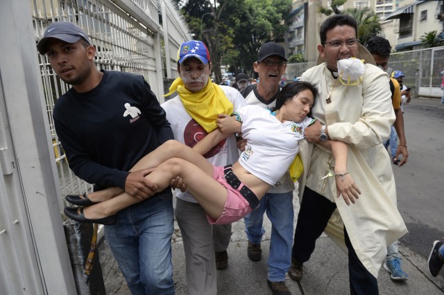 A woman receives attention during a march against President Nicolas Maduro, in Caracas on May 1, 2017. May Day protests risk being rough in Venezuela as it marks one month since deadly clashes erupted in a political crisis with no end in sight. Protesters took to the streets from April 1 to demand elections after the courts tried to strengthen President Nicolas Maduro's grip on power. / AFP PHOTO / FEDERICO PARRA