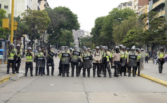 Policemen stand guard during an opposition march against President Nicolas Maduro, in Caracas on May 1, 2017. May Day protests risk being rough in Venezuela as it marks one month since deadly clashes erupted in a political crisis with no end in sight. Protesters took to the streets from April 1 to demand elections after the courts tried to strengthen President Nicolas Maduro's grip on power. / AFP PHOTO / FEDERICO PARRA