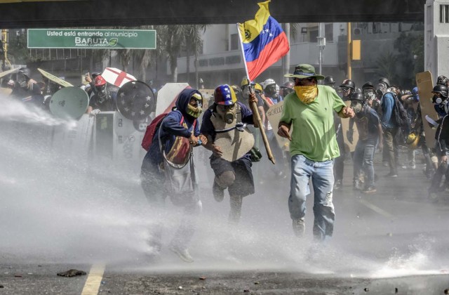 Opposition activists clash with the riot police during a demonstration against Venezuelan President Nicolas Maduro in Caracas, on May 26, 2017. Both the Venezuelan government and the opposition admit that violent protests that have gripped the country for nearly two months are out of control -- and analysts warn they could be a double-edged sword that might trigger even more unrest. / AFP PHOTO / JUAN BARRETO