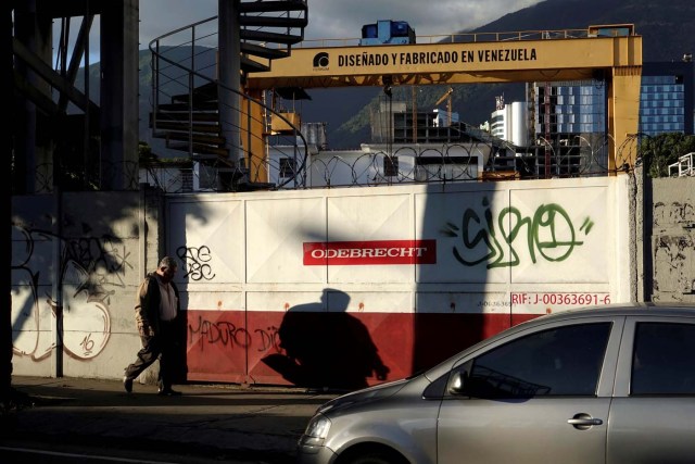 FILE PHOTO: A man walks past the corporate logo of Odebrecht at a construction site, with words (top) that read, "Designed and made in Venezuela" in Caracas, Venezuela January 26, 2017. REUTERS/Carlos Garcia Rawlins/File Photo
