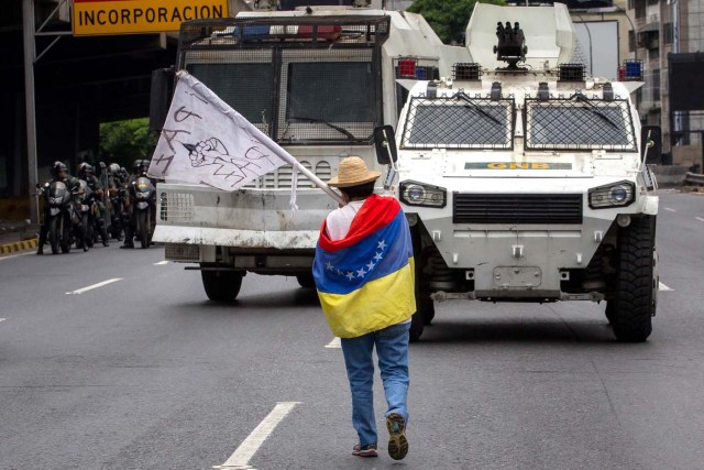 CAR009. CARACAS (VENEZUELA), 03/05/2017 - Una mujer bloquea el paso de una tanqueta de la Guardia Nacional durante una manifestación encabezada por diputados opositores hoy, miércoles 3 de mayo de 2017, en Caracas (Venezuela). La Guardia Nacional Bolivariana (GNB, policía militarizada) de Venezuela dispersó hoy con gases lacrimógenos una movilización opositora en el este de Caracas que pretendía llegar hasta la sede de la Asamblea Nacional (AN, Parlamento), ubicada en el centro de la capital. EFE/MIGUEL GUTIERREZ