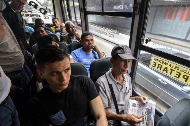 A group of people on a bus watch a presentation by reporters involved in the Bus TV news initiative in Caracas, Venezuela, on June 6, 2017. A group of young Venezuelan reporters board buses to present the news, as part of a project to keep people informed in the face of what the opposition and the national journalists' union describe as censorship by the government of Nicolas Maduro. / AFP PHOTO / LUIS ROBAYO