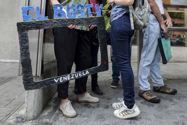 Laura Castillo (L) and Abril Mejias wait for a bus to give an on-board presentation of the Bus TV news in Caracas, Venezuela, on June 6, 2017. A group of young Venezuelan reporters board buses to present the news, as part of a project to keep people informed in the face of what the opposition and the national journalists' union describe as censorship by the government of Nicolas Maduro. / AFP PHOTO / LUIS ROBAYO