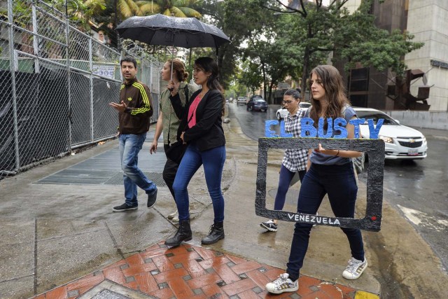 Dereck Blanco (L), Laura Castillo (C-1), Maria Gabriela Fernandez (C-2) and Abril Mejias (R) walk to a bus stop to give an on-board presentation of the Bus TV news in Caracas, Venezuela, on June 6, 2017. A group of young Venezuelan reporters board buses to present the news, as part of a project to keep people informed in the face of what the opposition and the national journalists' union describe as censorship by the government of Nicolas Maduro. / AFP PHOTO / LUIS ROBAYO