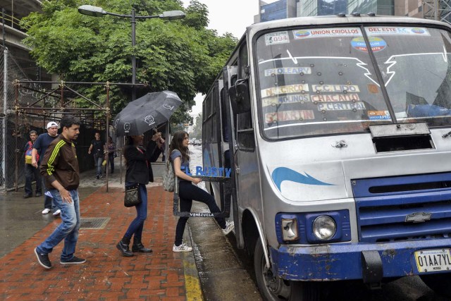 Dereck Blanco (L), Maria Gabriela Fernandez (C) and Abril Mejias board a bus to give a presentation of the Bus TV news in Caracas, Venezuela, on June 6, 2017. A group of young Venezuelan reporters board buses to present the news, as part of a project to keep people informed in the face of what the opposition and the national journalists' union describe as censorship by the government of Nicolas Maduro. / AFP PHOTO / LUIS ROBAYO
