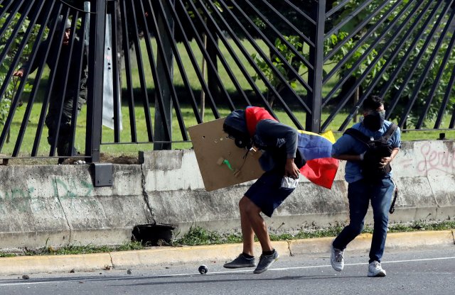 Un manifestante cubre con su escudo de cartón el cuerpo de David Vallenilla, ya gravemente herido a balazos por un sargento de la Policía Aérea de la base aérea La Carlota en  Caracas, Venezuela June 22, 2017. REUTERS/Carlos Garcia Rawlins