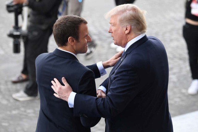 US President Donald Trump (R) and French President Emmanuel Macron shake hands at the end of the annual Bastille Day military parade on the Champs-Elysees avenue in Paris on July 14, 2017. The parade on Paris's Champs-Elysees will commemorate the centenary of the US entering WWI and will feature horses, helicopters, planes and troops. / AFP PHOTO / ALAIN JOCARD