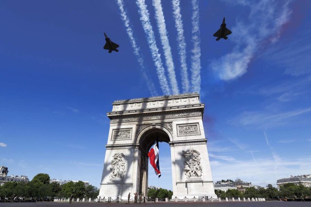 Two F22 of the US Air Force fly over the Arc de Triomphe on the Champs Elysees Avenue in Paris on July 14, 2017, during the Bastille Day military parade.  Bastille Day, the French National Day, is held annually each July 14, to commemorate the storming of the Bastille fortress in 1789. This years parade on Paris's Champs-Elysees will commemorate the centenary of the US entering WWI and will feature horses, helicopters, planes and troops. / AFP PHOTO / POOL / Etienne LAURENT