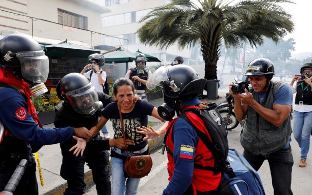 A woman is helped as she leaves a restaurant when smoke from tear gas fired by security forces got inside of it as clashes occured during a rally against Venezuelan President Nicolas Maduro's government in Caracas, Venezuela, July 6, 2017. REUTERS/Andres Martinez Casares