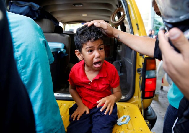 A child cries as he gets medical attention outside a shopping mall after smoke from tear gas fired by security forces got inside of it during clashes at a rally against Venezuelan President Nicolas Maduro's government in Caracas, Venezuela, July 6, 2017. REUTERS/Carlos Garcia Rawlins