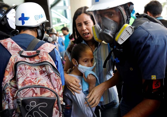 A woman and a girl get medical attention outside a shopping mall after smoke from tear gas fired by security forces got inside of it during clashes at a rally against Venezuelan President Nicolas Maduro's government in Caracas, Venezuela, July 6, 2017. REUTERS/Carlos Garcia Rawlins